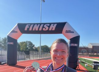 a woman at the finish line of a race holding her medal