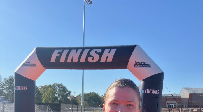 a woman at the finish line of a race holding her medal