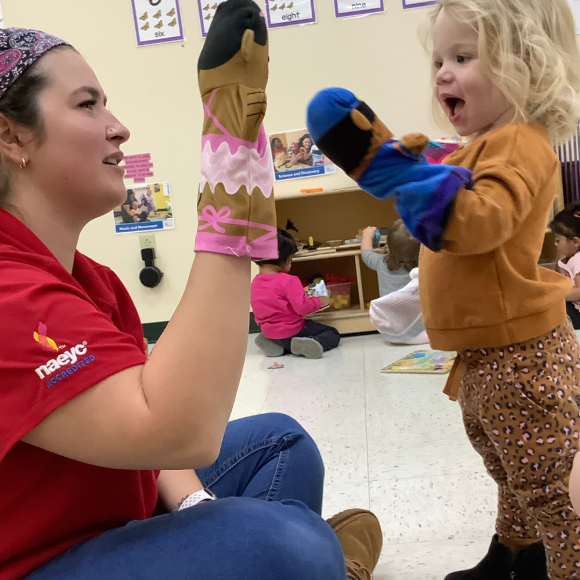 a child and teacher encouraging brain development while playing with puppets