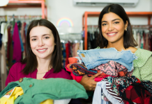 two moms with their arms full of clothing as they thrift shop