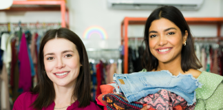 two moms with their arms full of clothing as they thrift shop