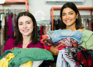 two moms with their arms full of clothing as they thrift shop