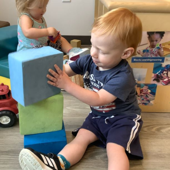 a young toddler stacking building blocks, enhancing brain development at a Kiddie Academy in St. Louis