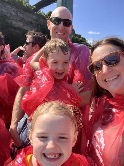 a family all wearing red rain ponchos in a post about working opposite shifts as parents