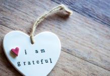 a white ceramic heart with the words, "I am grateful". There is a small red heart near the phrase