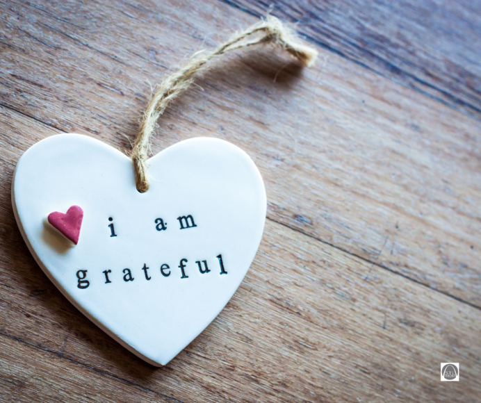 a white ceramic heart with the words, "I am grateful". There is a small red heart near the phrase