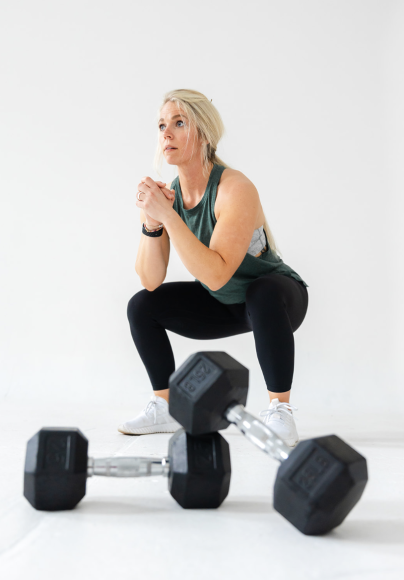 a woman doing a squat in front of a barbell as she works toward her fitness goals