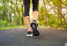 a close up of a woman's legs and feet as she takes a walk down a tree lined road