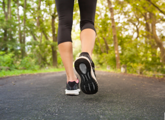 a close up of a woman's legs and feet as she takes a walk down a tree lined road