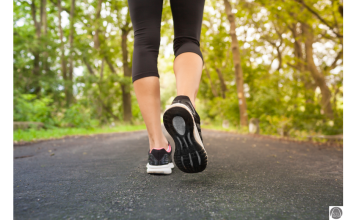 a close up of a woman's legs and feet as she takes a walk down a tree lined road