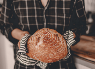No Shade to Sourdough, but … a woman wearing oven mitts as she holds a loaf of sourdough