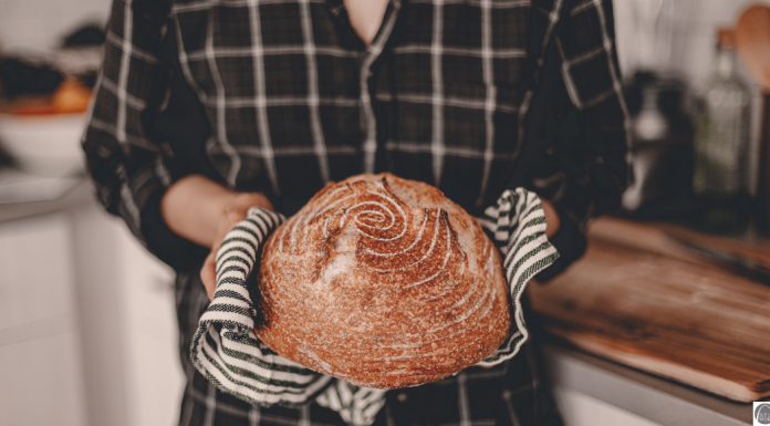 No Shade to Sourdough, but … a woman wearing oven mitts as she holds a loaf of sourdough