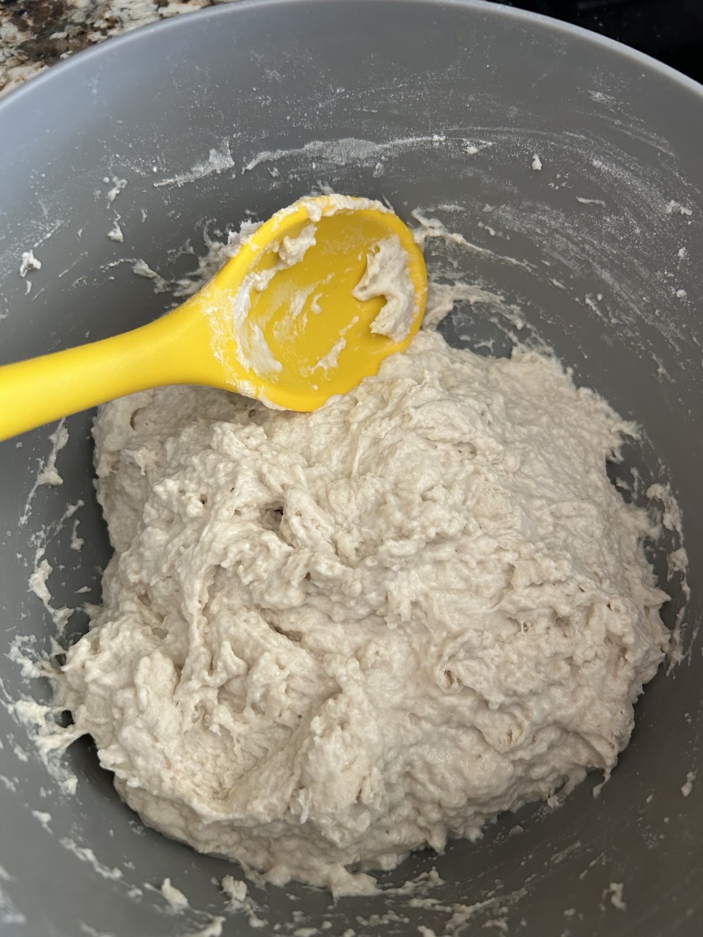 a spoon stirring dough to make sourdough bread