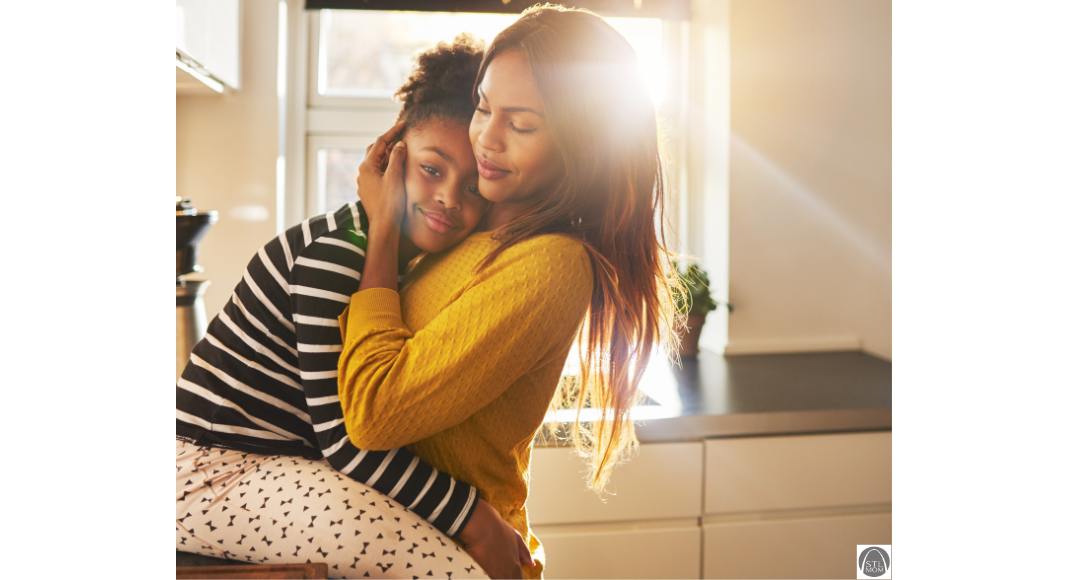 a good mom hugging her daughter who sits on the kitchen counter 