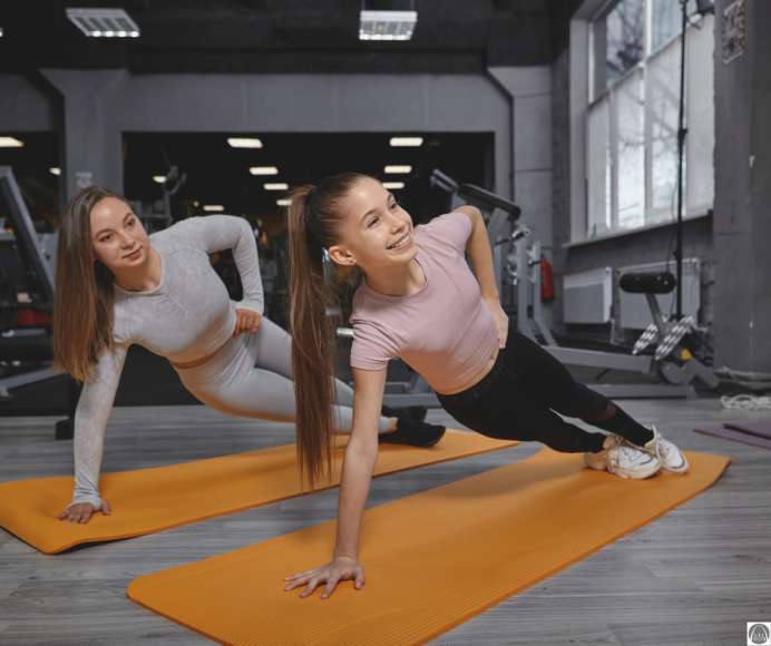 two teen girls on yoga mats doing planks as a fitness routine