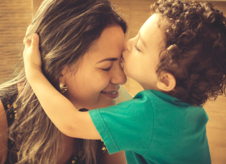a young boy kissing his mom's forehead