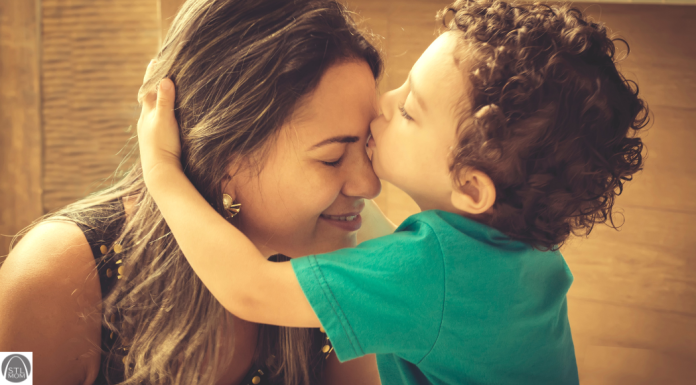 a young boy kissing his mom's forehead
