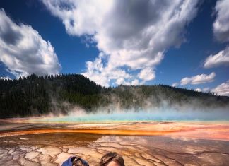 two boys standing in front of a geyser in Yellowstone, one of the National Parks