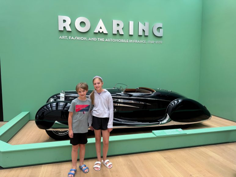 a young boy and young girl posing in front of an antique car at one of the family events at Roaring in St. Louis
