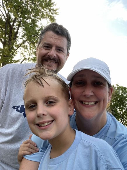 a mom, dad, and young boy posing for a photo at a swim meet