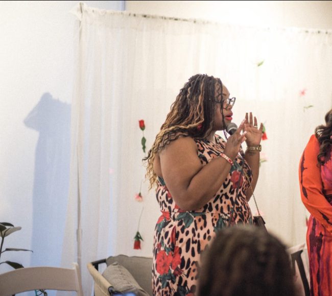 an African American woman using a microphone as she is speaking to a group