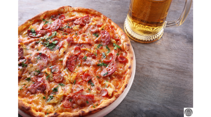 a close up of a pizza next to a stein of beer