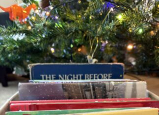 Making a Book List and Checking it Twice A candy-cane striped box of books under a Christmas tree.