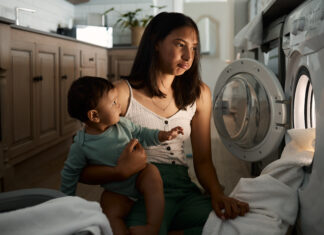 The Year I Stopped Living on Autopilot (And How You Can, Too) mom burnout autopilot Home, tired and mother with baby for laundry, household chores and parenthood with machine. House, child and mom with burnout expression to wash clothes, responsibility or electric appliance at night.